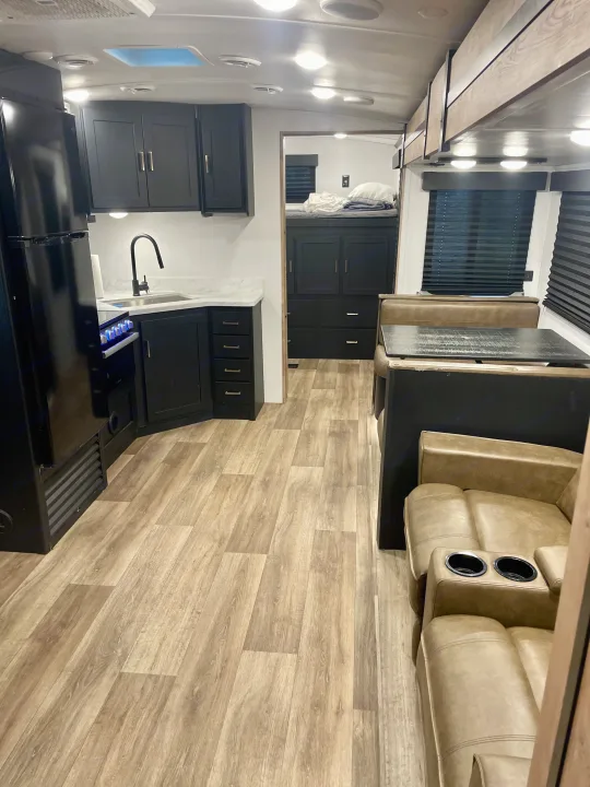 Spacious RV rental interior featuring a modern kitchen, dining booth, and cozy bunk beds. Perfect for your next adventure.. Keystone Outback 2022