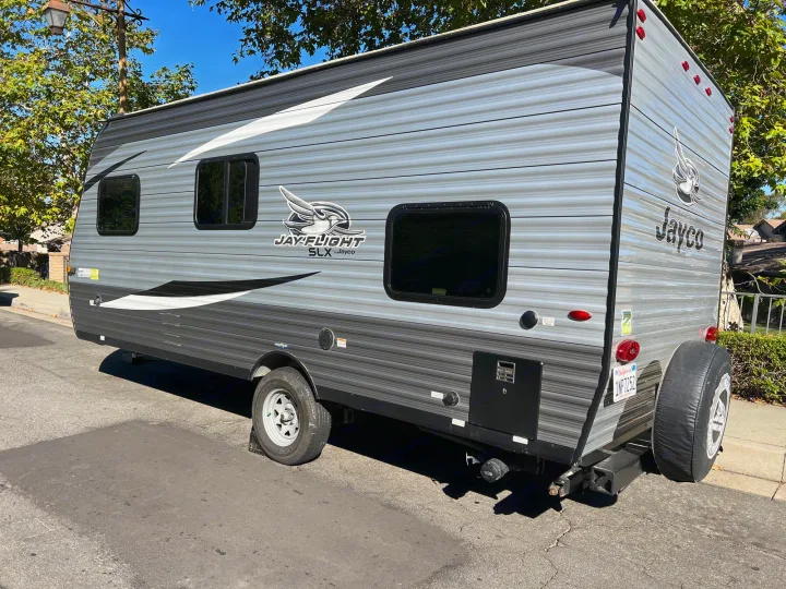 This gray Jayco Jay Flight SLX travel trailer, perfect for an RV rental, is parked on a sunny street.. Jayco Jay Flight 2021
