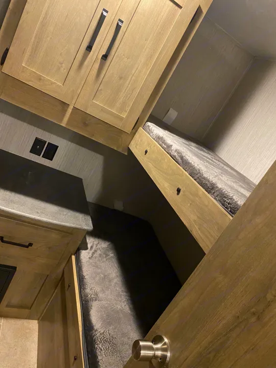 Explore this RV rental's cozy bunk beds, light wood cabinets, and functional counter space, ideal for trips.. Forest River Palomino Puma XLE Lite 2021