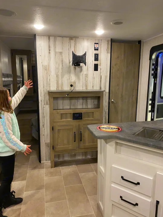Cozy RV rental interior with kitchen island, entertainment unit, and a child exploring. Perfect for family adventures.. Forest River Palomino Puma XLE Lite 2021