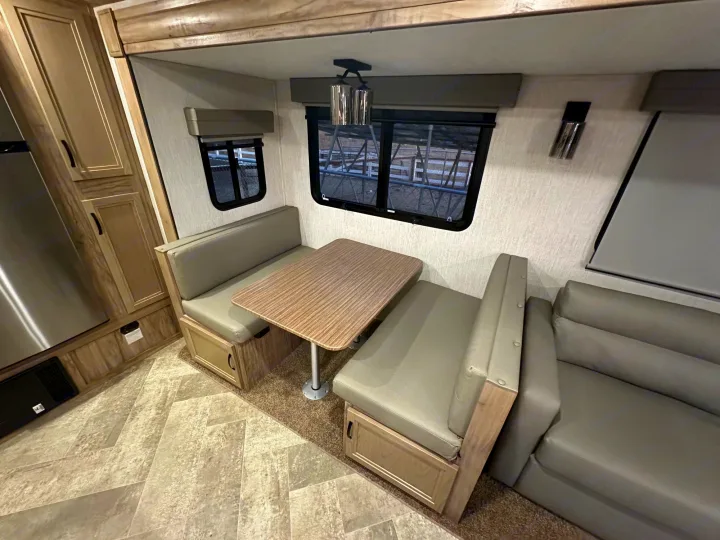 This RV rental features a cozy dinette with a table, sofa, and modern interior finishes like wood cabinets and patterned flooring.. Palomino Salaire Ultralite 2022