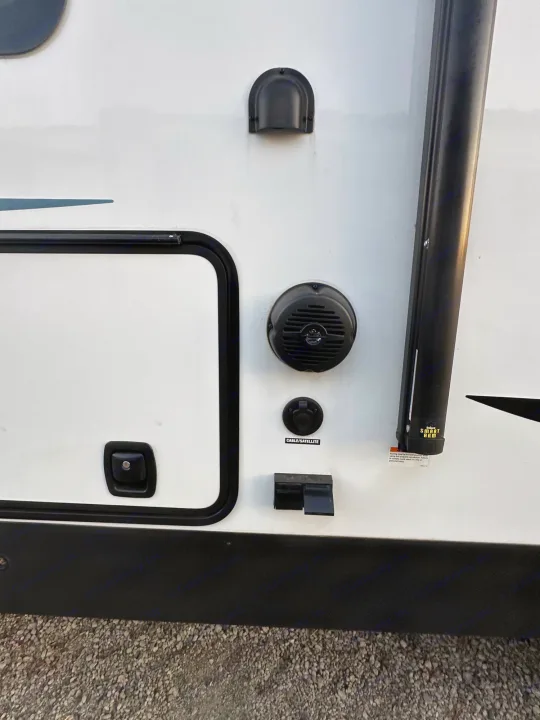 RV rental exterior: Awning arm, speaker, cable/satellite, and other utility hookups on a white travel trailer side.. Palomino Salaire Ultralite 2022