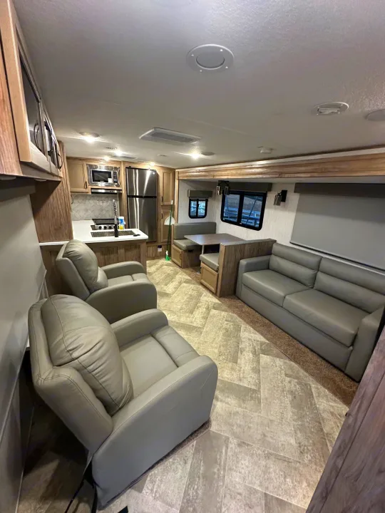 Bright rv rental living area featuring a modern kitchen, dining booth, comfortable sofa, and two recliners.. Palomino Salaire Ultralite 2022