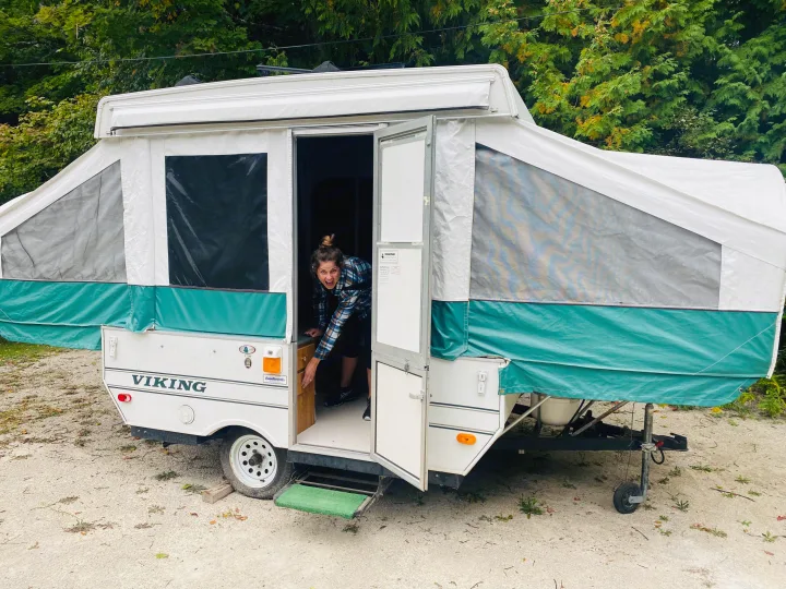A cheerful woman peeks from her pop-up camper, ready for adventure in her rv rental.. Viking Recreational Vehicles, INC. Model 548 2000