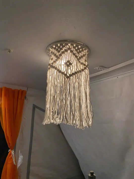 Cozy RV rental interior with a bright macrame pendant light. Orange curtains and simple decor enhance the space.. Viking Recreational Vehicles, INC. Model 548 2000