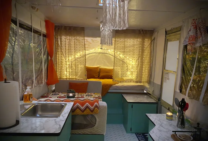 Cozy, decorated RV rental interior with macrame lights, a comfy bed, and a functional dinette/kitchenette.. Viking Recreational Vehicles, INC. Model 548 2000