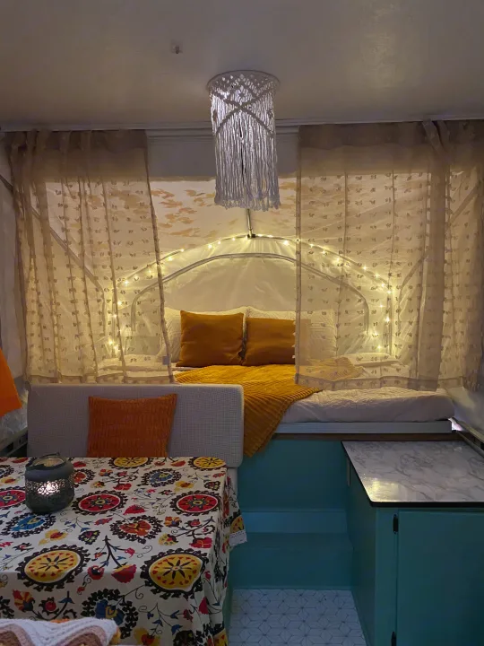Step inside this cozy RV rental! Features an illuminated bed area, macrame light, vibrant dining space, and teal cabinet accents.. Viking Recreational Vehicles, INC. Model 548 2000