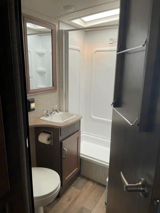 Compact RV rental bathroom with sink, toilet, and shower. Efficient design for comfortable travels.. Winnebago Sunstar 2021
