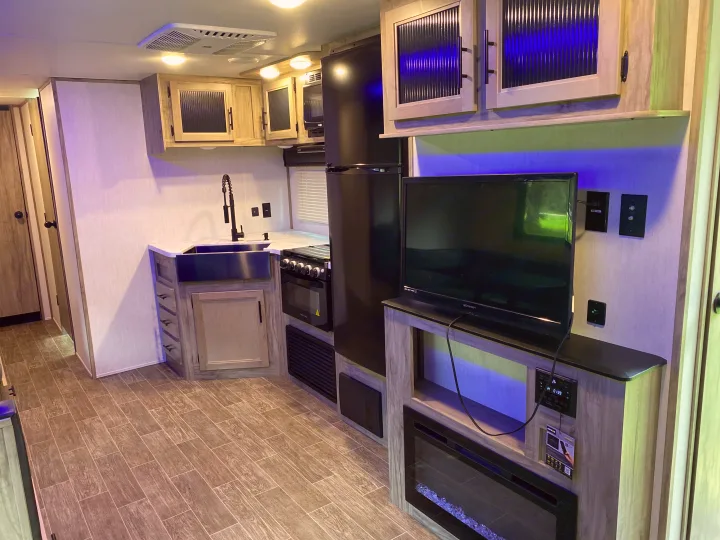 Inside this rv rental, find a sleek kitchen with a large sink, full-size fridge, and entertainment center with TV/fireplace.. Forest River Cherokee Alpha Wolf 2022