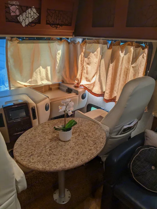 Cozy rv rental interior with a small table, swivel chairs, and curtains, offering a comfortable living space.. Thor ACE 30.2 2015