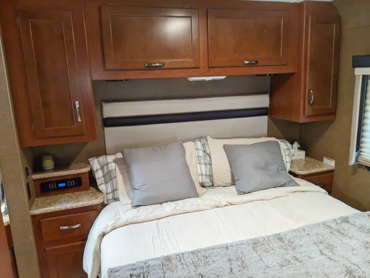 RV rental bedroom: cozy bed with plush pillows, dark wood cabinets, and functional nightstands.. Thor ACE 30.2 2015