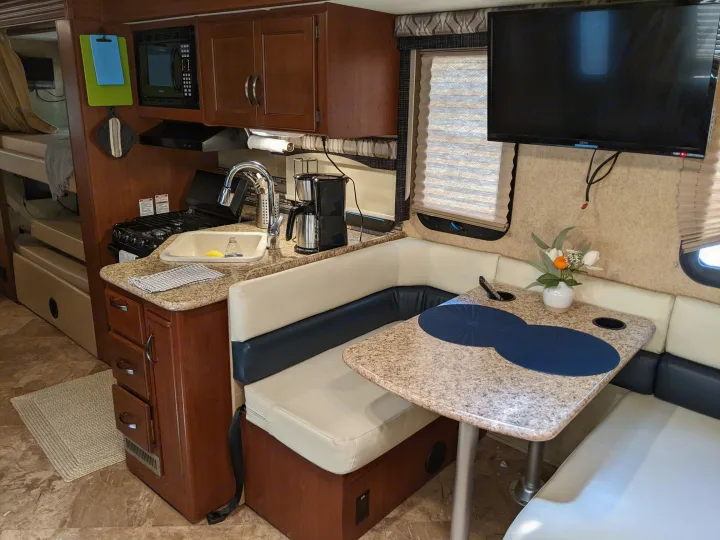 RV rental interior: compact kitchen, dinette, and bunk beds, with a TV for entertainment.. Thor ACE 30.2 2015