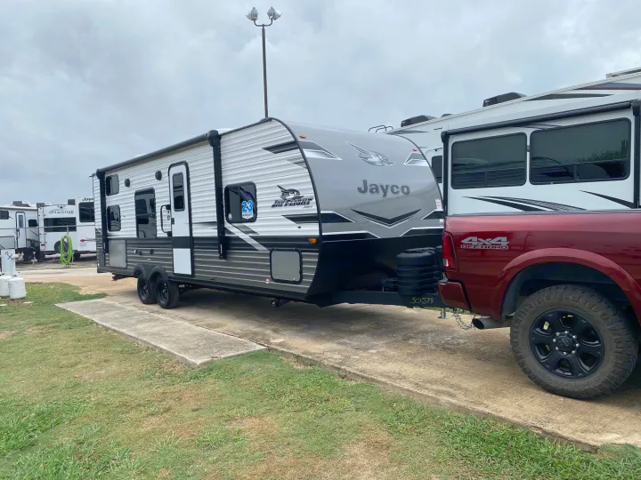 RV rental: A grey Jayco travel trailer hitched to a red truck, parked on concrete at an RV park.. Jayco Jay Flight 264BH 2024