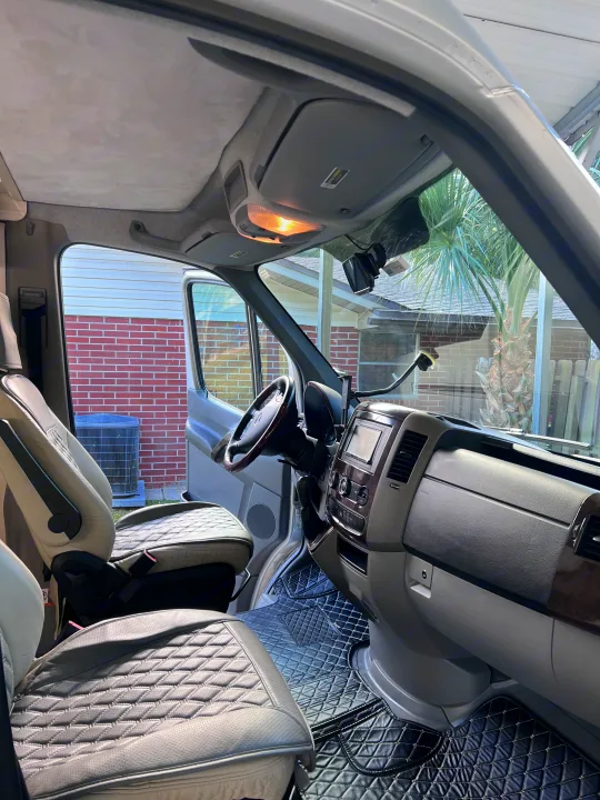Clean RV rental's front cabin interior. Features bright, quilted leather seats, dashboard, and custom floor mats for travelers.. Airstream Interstate 2012