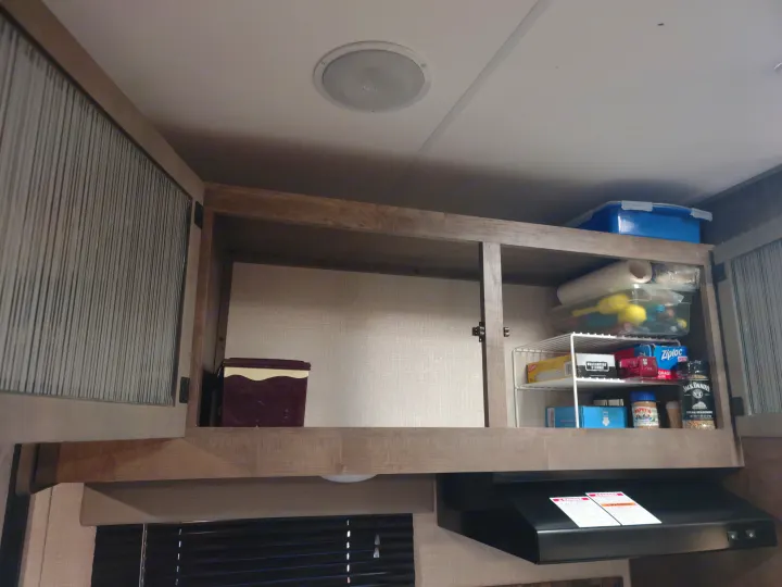 This RV rental features organized kitchen cabinets with supplies, a range hood, and a ceiling light.. Sonic Lite 2021