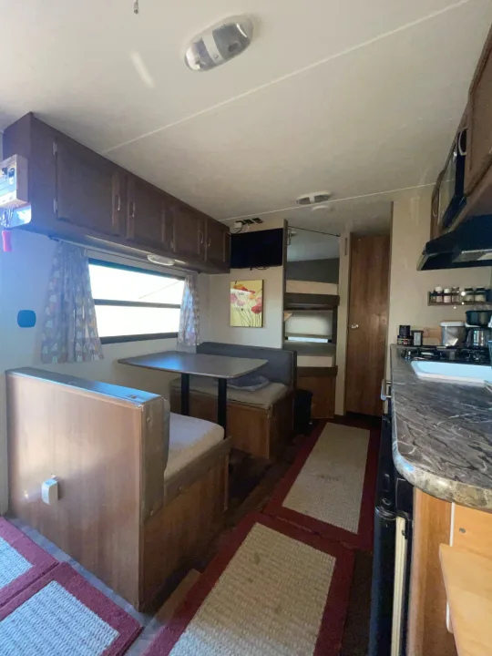 Explore this inviting RV rental interior, featuring a functional dinette, well-equipped kitchen, and cozy bunk beds.. Keystone RV Summerland Mini 2017