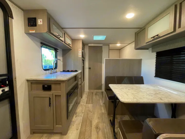Modern rv rental interior features a functional kitchen, cozy dinette, and durable wood-look flooring.. Coleman Lantern 17B 2024
