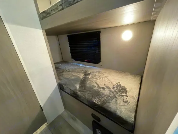 Step inside this cozy RV rental's bunk beds, featuring a window, light, and compact interior space for adventure.. Coleman Lantern 17B 2024