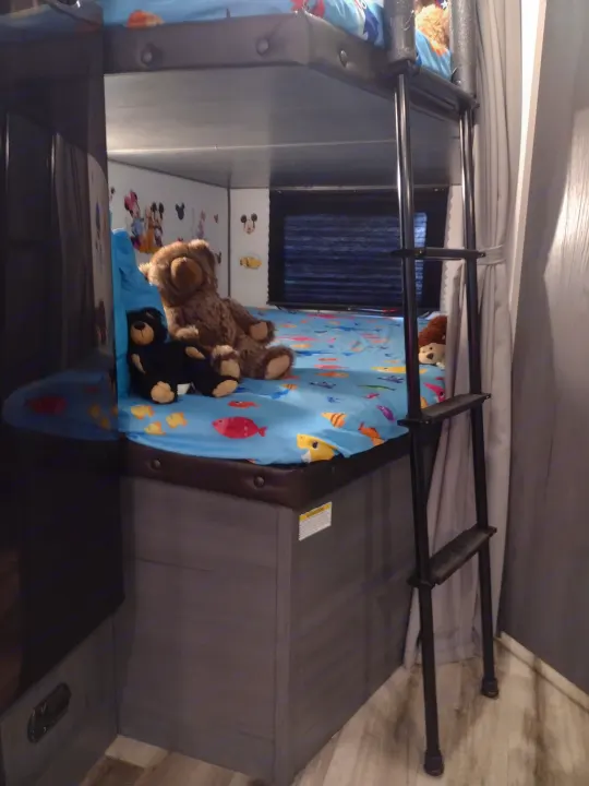 Kid-friendly RV rental bunk bed with stuffed animals, a fish sheet, and cartoon decals for a cozy stay.. Aspen Trail LE 2024