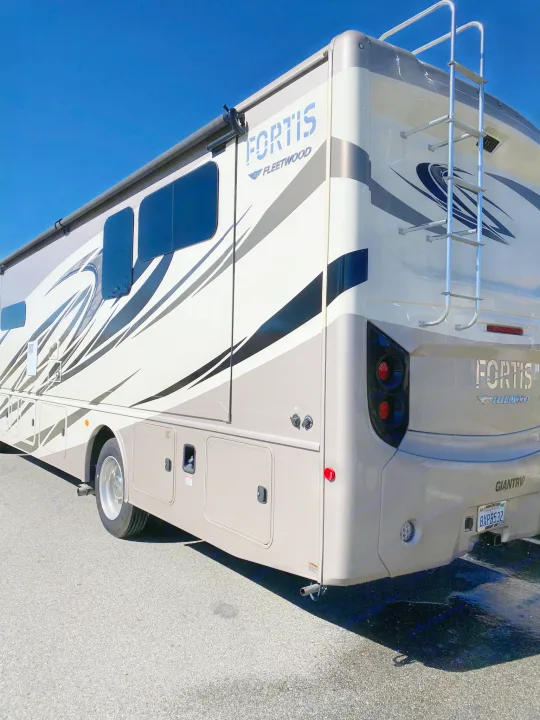 This sleek Fleetwood Fortis RV, perfect for an RV rental, shows its modern design, awning, and rear ladder.. Fleetwood Fortis 2021