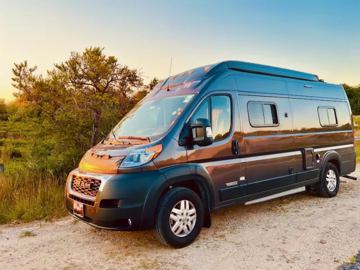 This sleek gray camper van (RV) parked on a dirt road is perfect for an RV rental adventure in nature.. Winnebago Solis 2023
