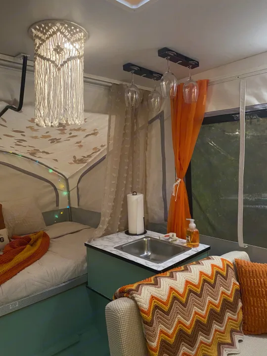 Cozy rv rental interior: Bed, sink, decorative macrame light, wine glasses, & colorful blankets. A stylish camper retreat.. Viking Recreational Vehicles, INC. Model 548 2000