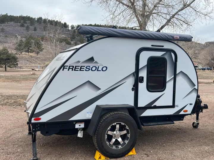 White "FREESOLO" teardrop RV rental parked at a mountain campsite, ready for outdoor adventure.. Braxton Creek Free Solo 2022