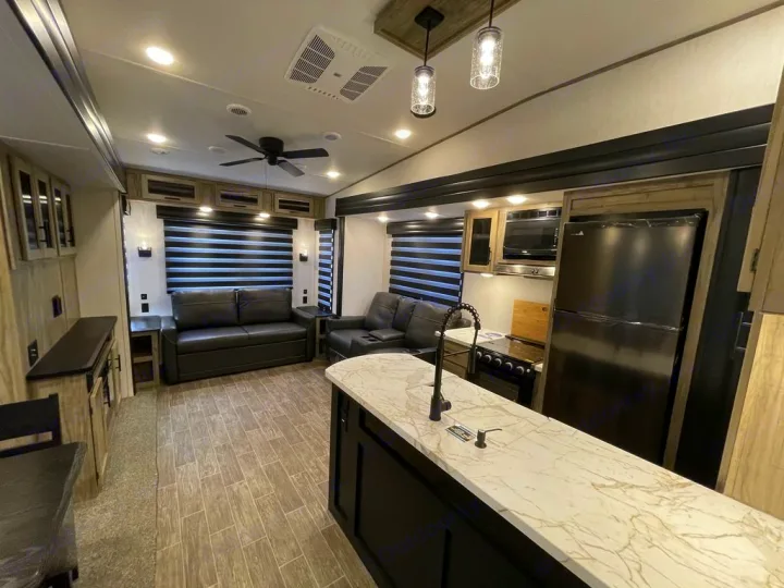 Modern RV rental interior showcasing a spacious living area and fully-equipped kitchen with island.. Forest River Cherokee Arctic Wolf 2022