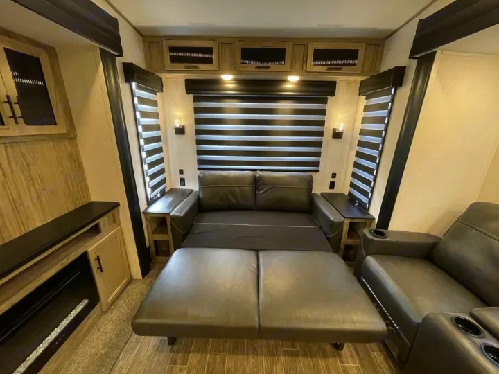 Spacious RV rental living area featuring a pull-out sofa bed, recliners, and warm ambient lighting.. Forest River Cherokee Arctic Wolf 2022