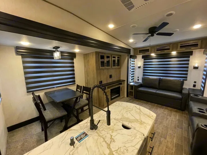 Inviting RV rental interior: kitchen island, dining table, comfy sofa, and fireplace in the living space.. Forest River Cherokee Arctic Wolf 2022