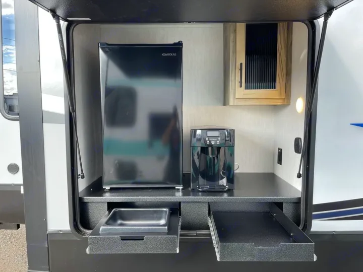 RV rental: Outdoor kitchen with black mini-fridge, Keurig coffee maker, and pull-out trays for convenient use.. Forest River Cherokee Arctic Wolf 2022
