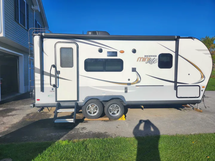 Rockwood Minilite RV rental. White travel trailer with awning & steps, parked on pavement, clear blue sky.. Forest River Rockwood Mini Lite 2019