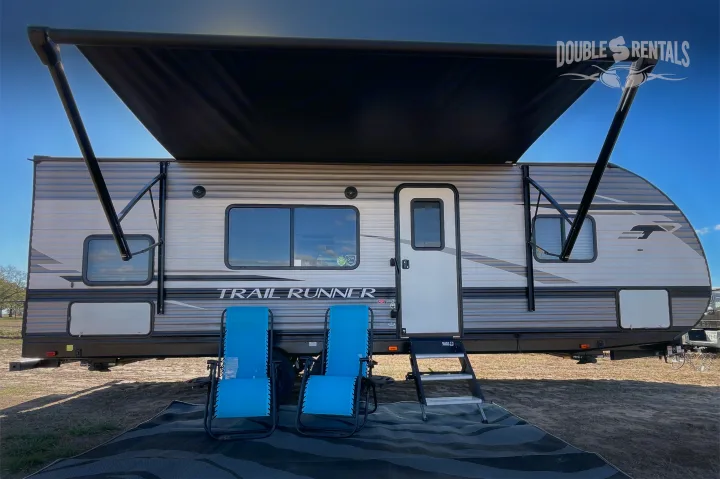 "Trail Runner" RV rental ready for adventure: Features extended awning & comfortable blue chairs for outdoor relaxation.. Heartland Trail Runner 2021