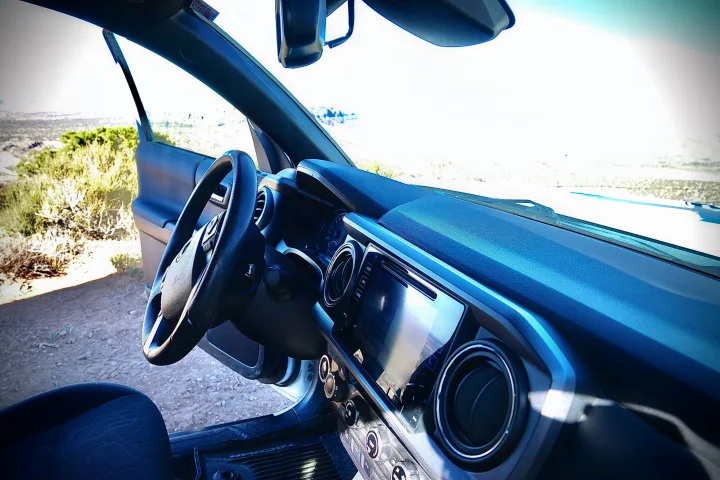 Interior view of a Toyota Tacoma truck with an open door to a vast dry landscape, ideal for travel or an rv rental.. toyota tacoma trd 4x4 2018