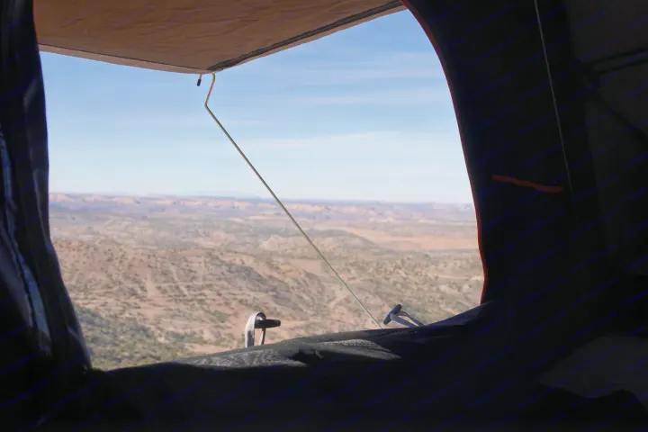 Scenic RV rental view from inside: a vast desert landscape with mesas under a blue sky, seen through a tent window.. toyota tacoma trd 4x4 2018