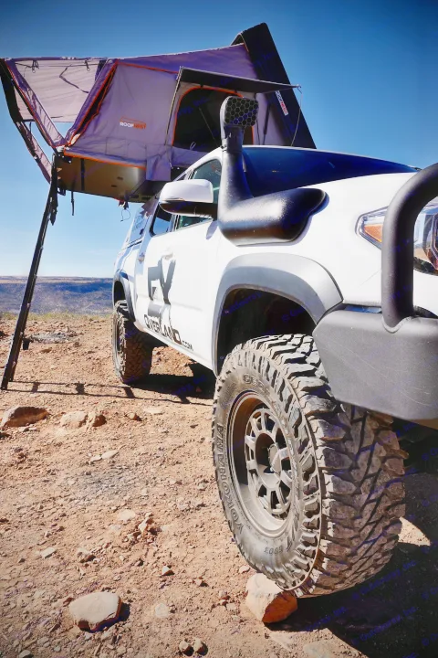 White overland vehicle with a Roofnest roof-top tent deployed on rocky terrain. Ideal for an RV rental off-road camping trip.. toyota tacoma trd 4x4 2018