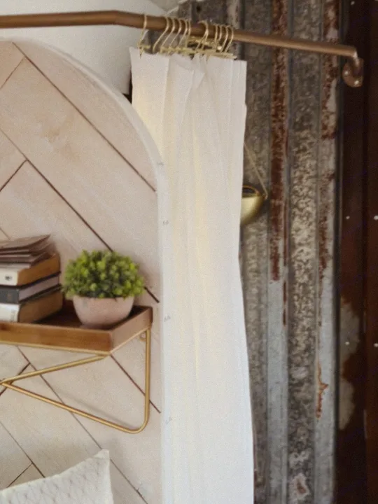 Cozy RV rental interior featuring stylish white curtains on a gold rod, a rustic metal wall, and a shelf with a plant.. Ford E450 1999