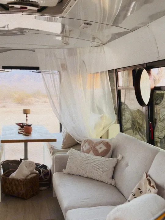 Step into this cozy rv rental! Bright interior with a comfortable sofa, dining area, sheer curtains, and a desert view.. Ford E450 1999