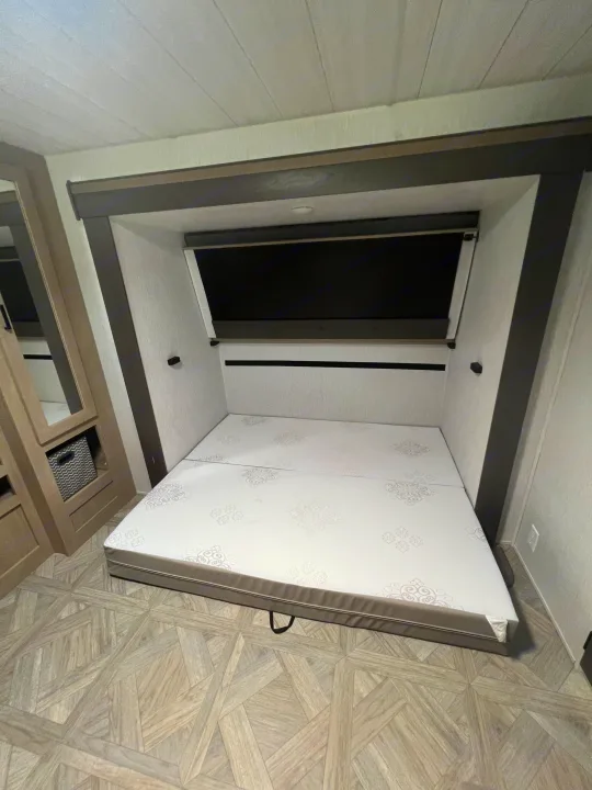 RV rental bedroom featuring a two-piece mattress and modern patterned flooring, ready for use.. Forest River 31KQBTS 2024