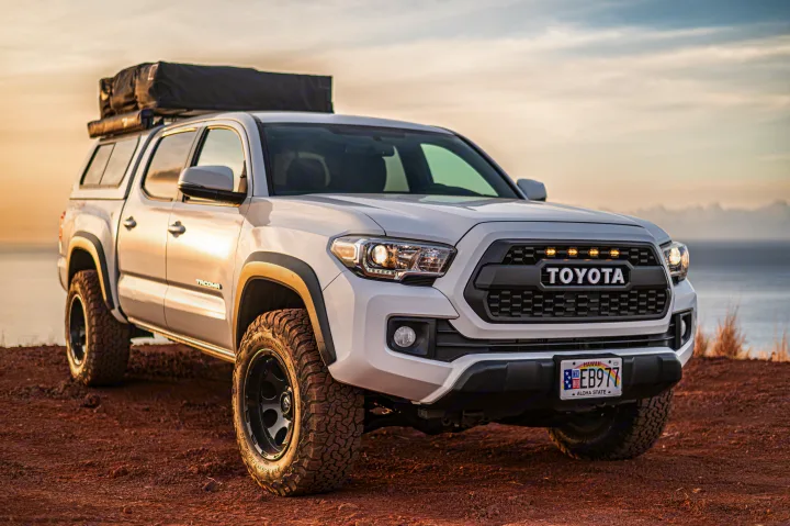 A white Toyota Tacoma truck with a rooftop tent, ideal for your next outdoor adventure or **RV rental** road trip by the sea.. Custom Camper 2016