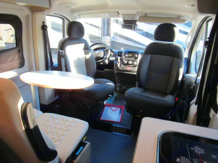 Inside an RV rental: front seats swivel to face a round table and rear seating, creating a cozy living space.. Winnebago Solis 2022