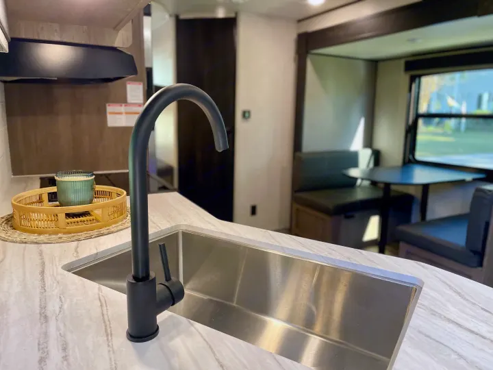 Spacious RV rental kitchen with modern black faucet, deep sink, and cozy dining area, ideal for travel.. Starcraft Autumn Ridge 2023