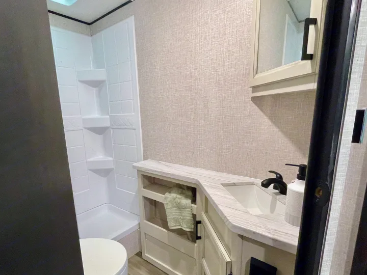 Well-appointed RV rental bathroom with white shower, sleek vanity, sink, and mirror cabinet for comfortable travel.. Starcraft Autumn Ridge 2023