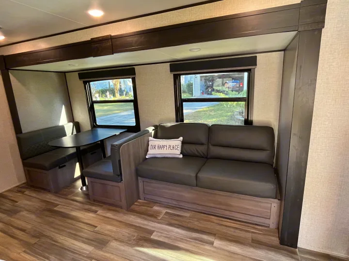 Inside a modern RV rental, showing a comfortable dinette with bench seating and a plush sofa, ideal for relaxation on the go.. Starcraft Autumn Ridge 2023