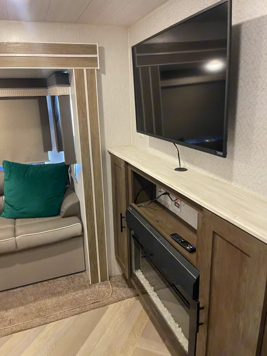 This RV rental's living space features a wall-mounted TV above an electric fireplace, next to a comfy sofa.. Forest River Salem 2022
