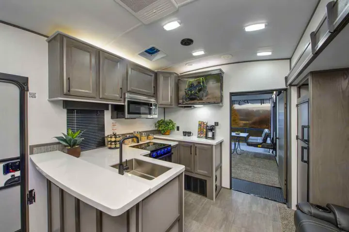 Modern RV rental interior: spacious kitchen with gray cabinets, TV, and outdoor deck access.. Cruiser Rv Corp Stryker 2022