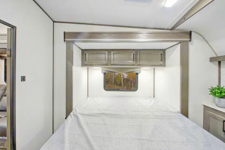 Cozy RV rental bedroom featuring a comfortable bed, overhead cabinets, and a window. Ideal for compact travel.. Cruiser Rv Corp Stryker 2022