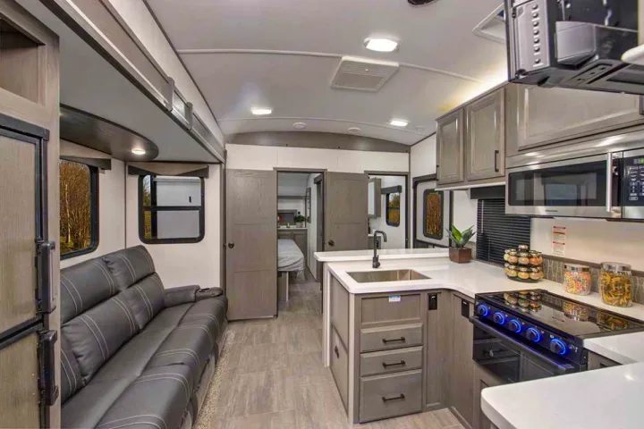 Explore this RV rental's modern interior: well-equipped kitchen, comfy living area with sofa, and accessible bedroom beyond.. Cruiser Rv Corp Stryker 2022
