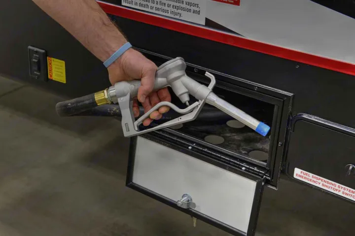 A hand inserts a gray fuel nozzle into an RV rental's fuel port, showing the vehicle being refueled.. Cruiser Rv Corp Stryker 2022