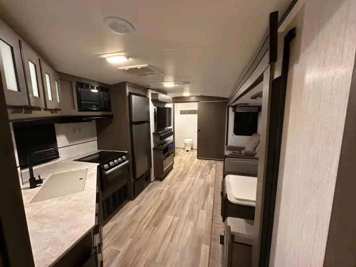 This modern rv rental interior features a full kitchen, comfortable living area, and rear bathroom access.. Cruiser RV MPG Ultra Lite 2022